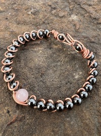 a bracelet with a pink stone and copper wire