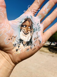 a person's hand with a face painted on it