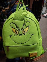 a green backpack with a grin on it