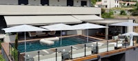 a swimming pool with lounge chairs and umbrellas on top of a house