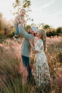 a family in a field holding their baby in the air