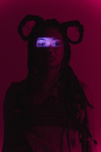 a woman with dreadlocks in front of a pink light
