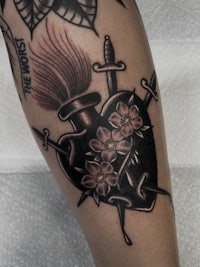a tattoo of a heart with a sword and flowers