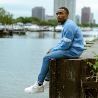 a man in a blue sweater sitting on a pier