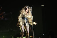 a woman in a gold outfit singing on stage