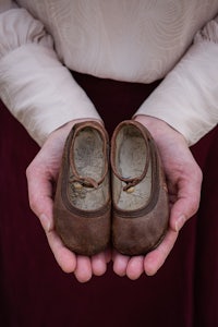 a woman's hands holding a pair of brown shoes