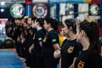 a group of people in black t - shirts standing in a gym