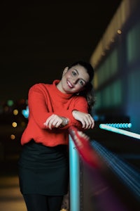 a woman leaning against a railing at night