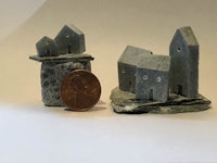 miniature houses on a rock next to a penny