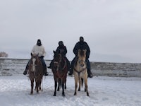 three people riding horses in the snow