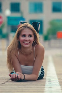 a young woman laying on a sidewalk