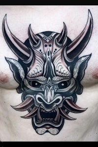 a tattoo of a demon with horns on his chest