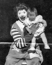 an old photo of a clown holding a child