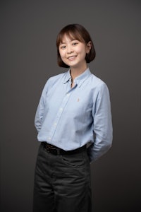 a young asian woman in a blue shirt and black pants