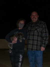 a man and woman holding a puppy at night