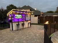 a backyard bar with purple lights and a fire pit