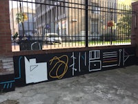 a wall with graffiti on it and a fence in the background