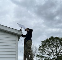 a man installing a solar panel on the roof of a house