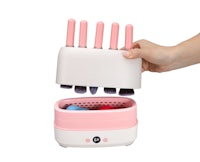 a hand holding a pink and white makeup brush holder