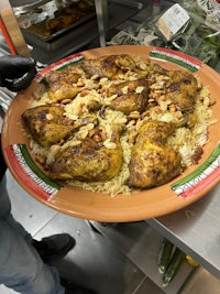 a plate of chicken with rice and vegetables on a counter