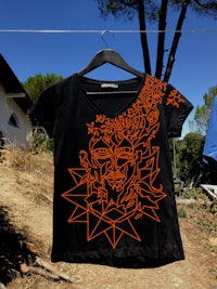 a black t - shirt with an orange design on it