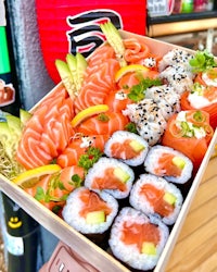 a box full of sushi and vegetables