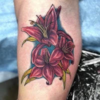 a tattoo of red lilies on the forearm