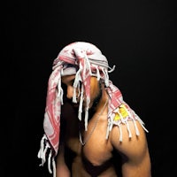 a man with a scarf on his head posing in front of a black background