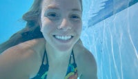 a young woman smiling underwater in a swimming pool
