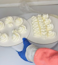 a person is putting frosting on a white plate