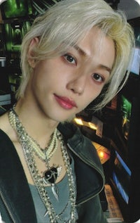 a young man with blond hair and a necklace