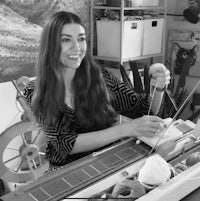 black and white photo of a woman knitting on a machine