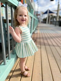 a little girl wearing a green and white striped dress