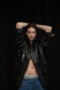 a woman in a black leather jacket posing on a black background