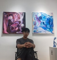 a man in a wheelchair sitting in front of two paintings