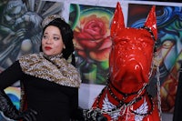 a woman is standing next to a red dog statue