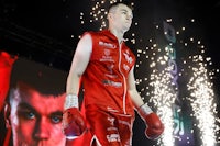 a boxer in red standing on a stage with fireworks