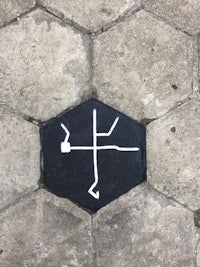 a sign with a cross on it on a sidewalk