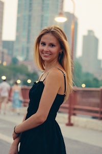 a young woman in a black dress posing on a bridge