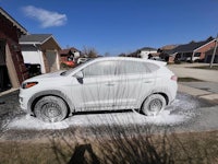a white hyundai tucson is being washed in a driveway