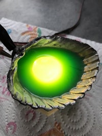 a person is holding a bowl with a green light in it