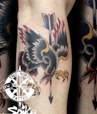 a tattoo of a crow with an arrow