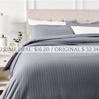 a bed with a grey stripe duvet cover and pillows