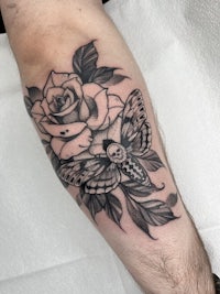 a black and white tattoo of roses and a butterfly