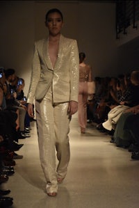 a model walks down the runway in a white suit