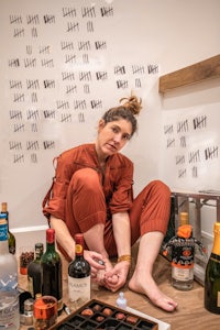 a woman sitting on the floor with a bottle of alcohol
