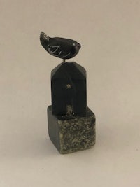 a black bird sits on top of a stone block