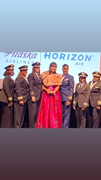 a group of pilots and flight attendants posing in front of an alaska horizon sign