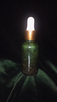 a green glass bottle with a gold lid