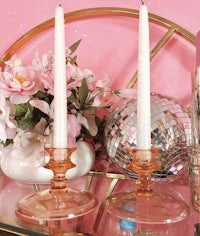 a set of pink glass candle holders on a pink table